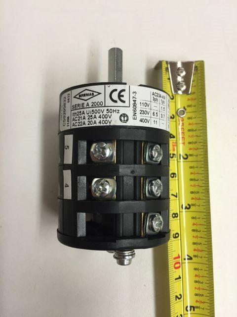 Black electrical terminal block beside a yellow measuring tape on a white background