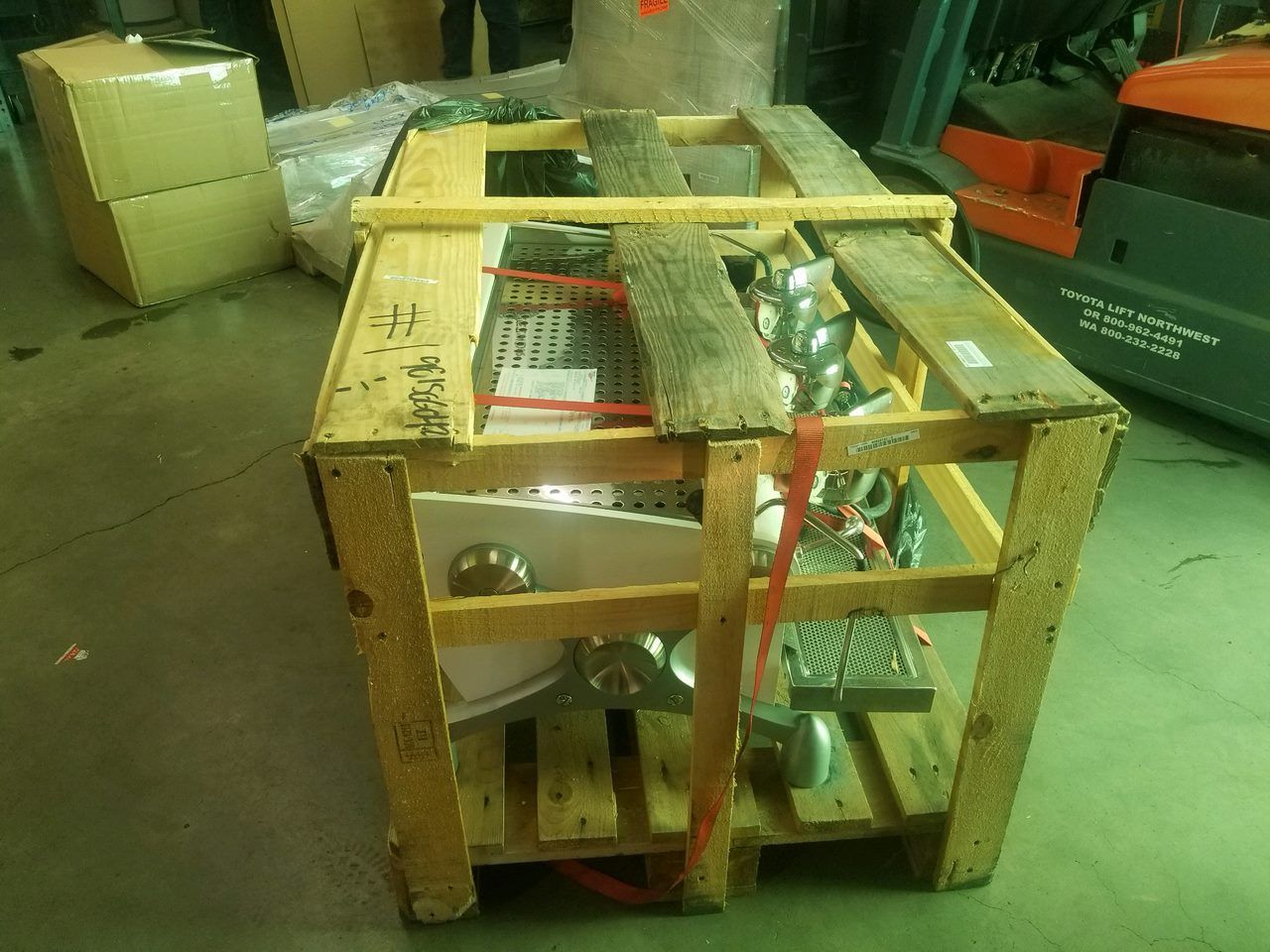 Wooden crate with a large machine or equipment strapped inside in a warehouse.