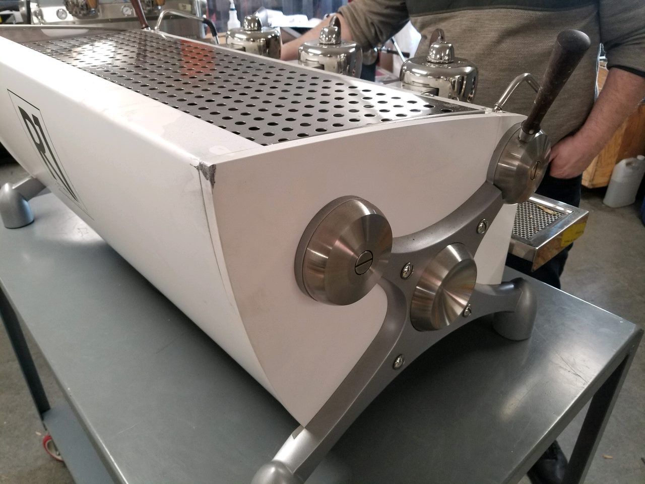 Stainless steel espresso machine on a counter in a café or kitchen.