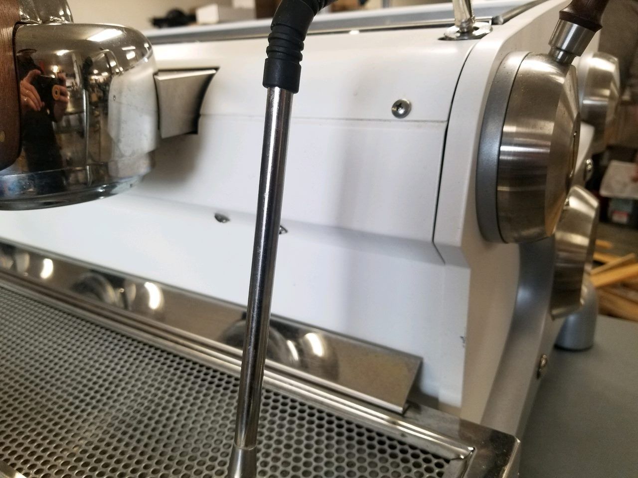 Close-up of a chrome espresso machine with a steam wand over a drip tray.
