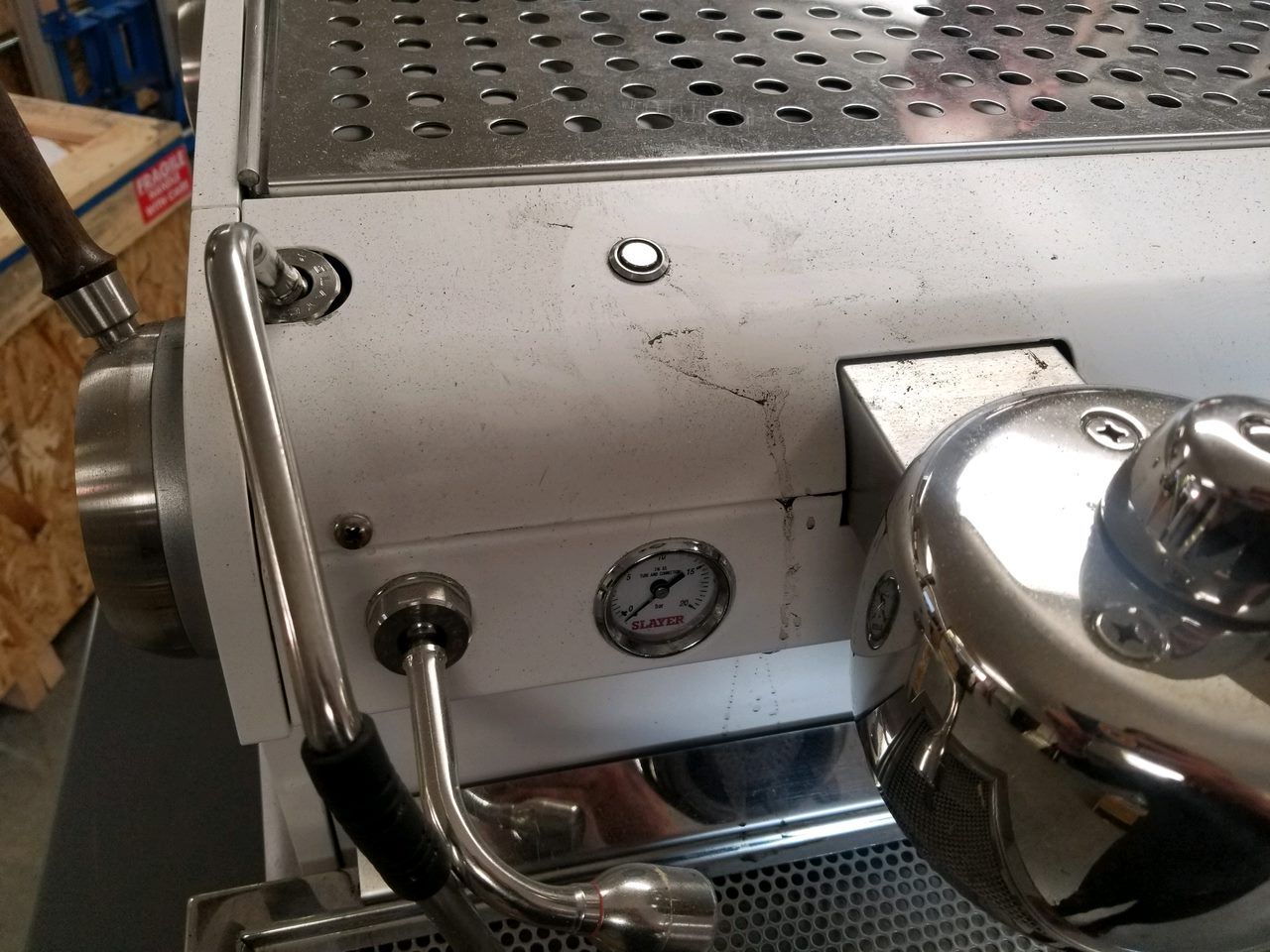 Stainless steel espresso machine with a pressure gauge and chrome steam knob in a café setting