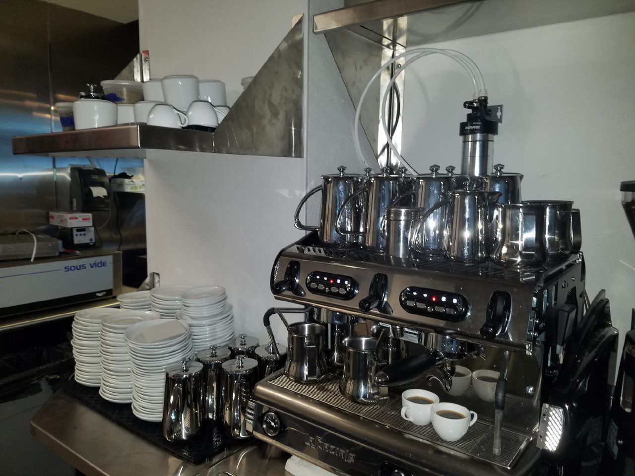 Coffee bar with shiny espresso machine, stacked cups, and saucers on a counter