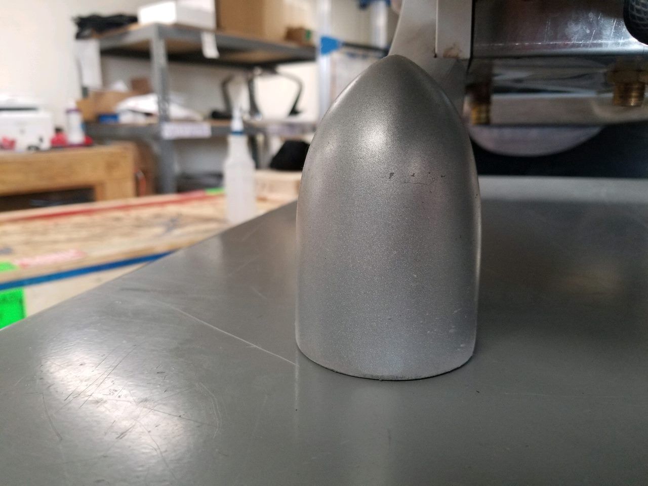 Gray rounded metal object on a tabletop in a workshop setting