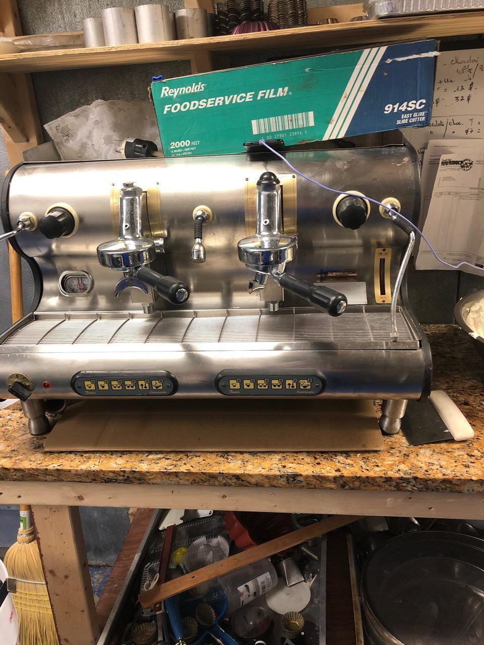 A stainless steel coffee machine is sitting on top of a wooden table.