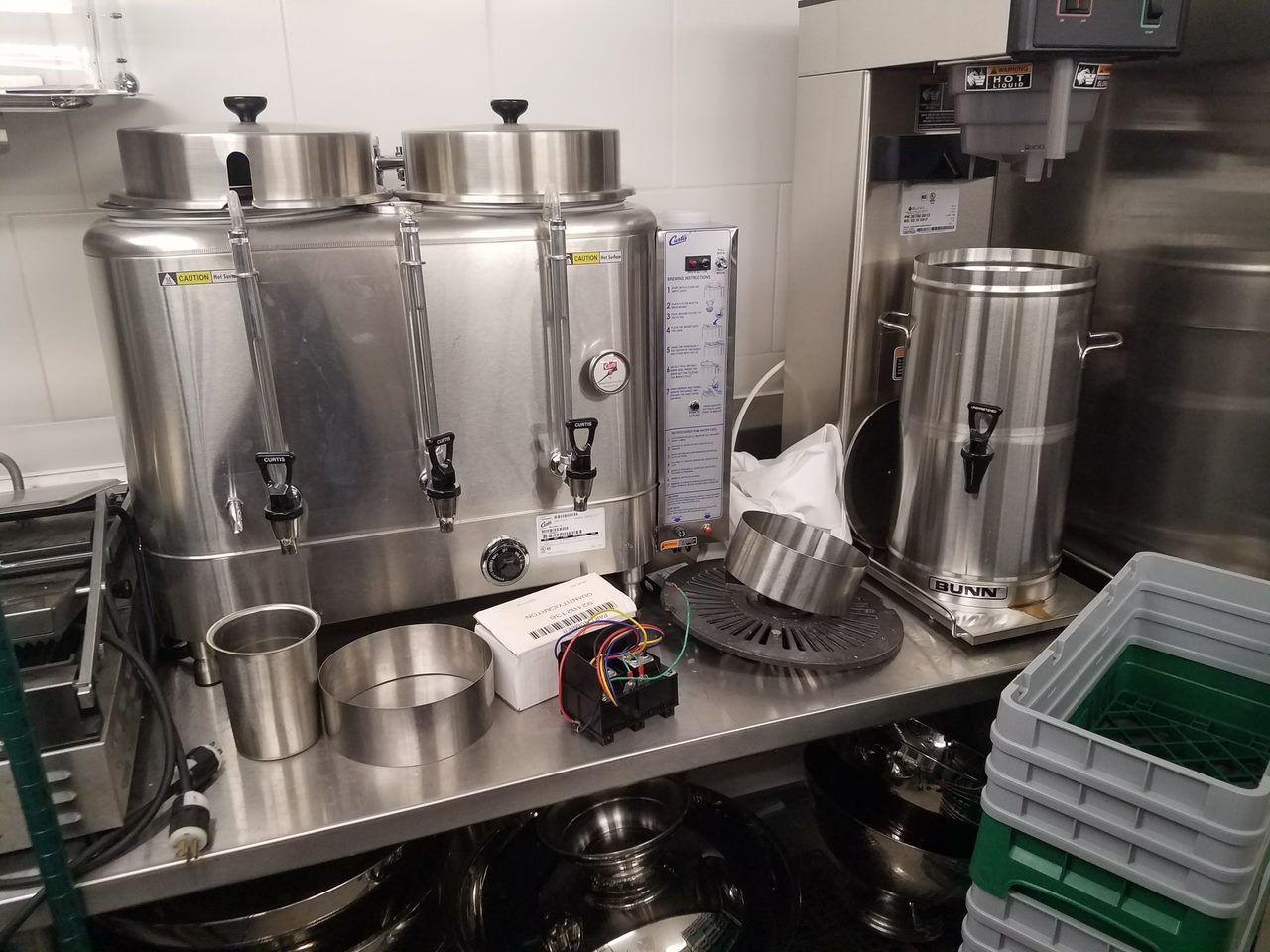 Industrial kitchen with stainless steel equipment, sinks, and stacked trays on a counter
