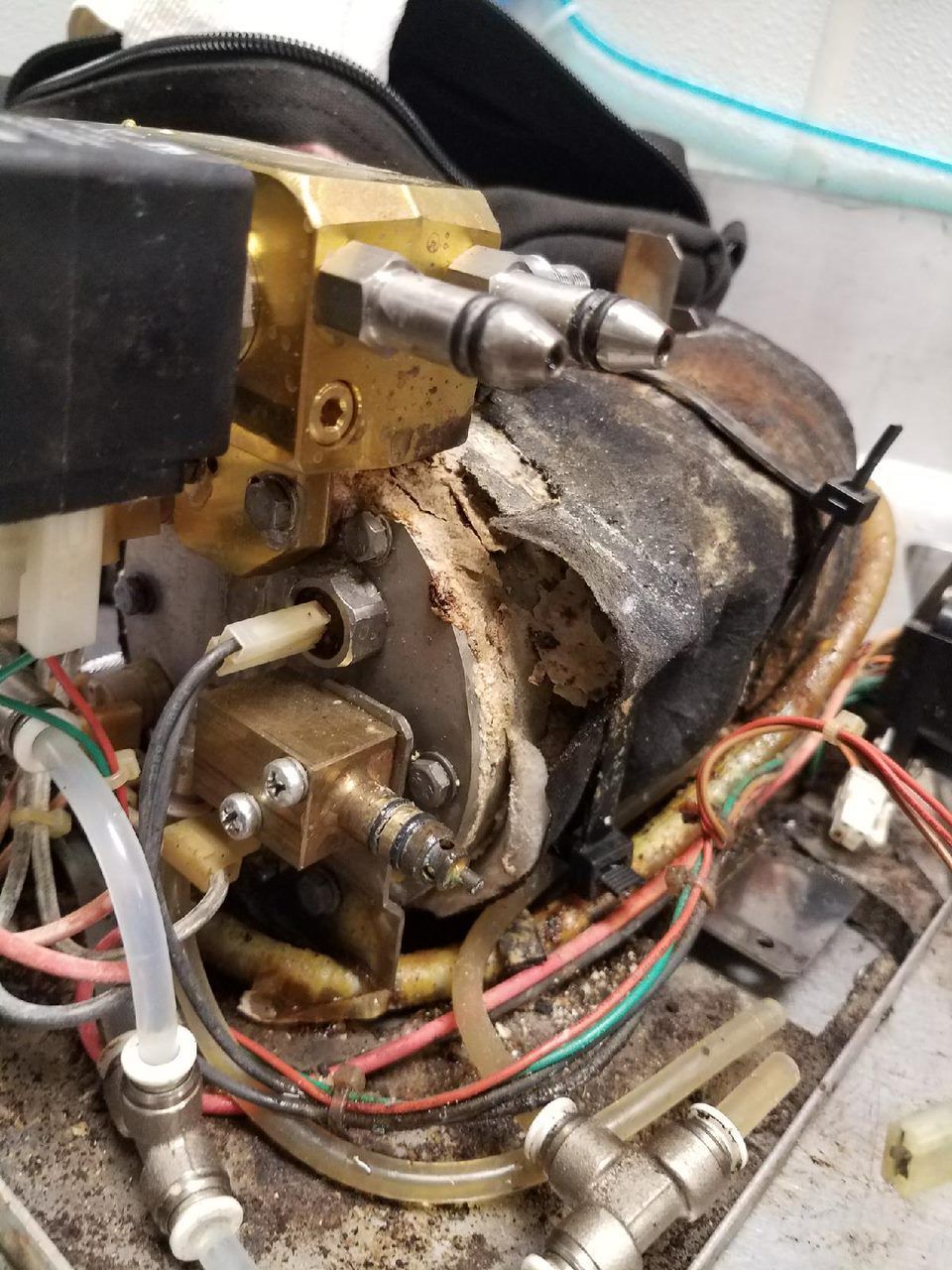 Close-up of a burnt mechanical component with wires, metal fittings, and charred insulation.