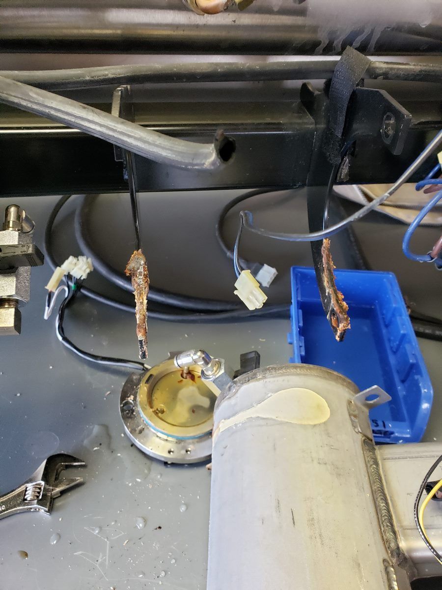 Worn lab setup with hanging wires, blue tray, and scattered debris on a dark surface