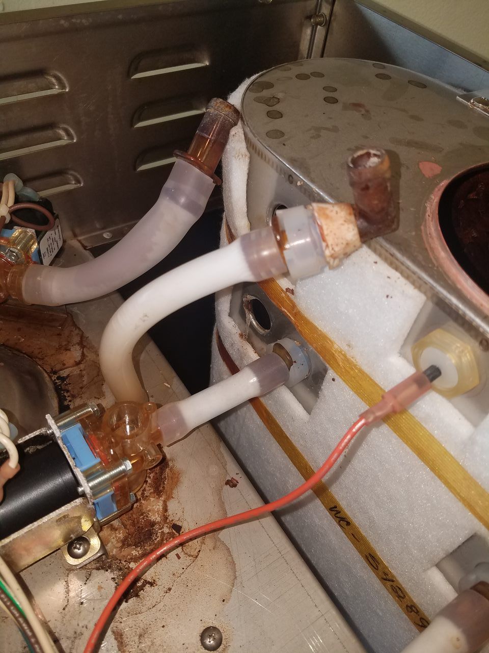 Close-up of white tubing and wires connected to a metal appliance interior