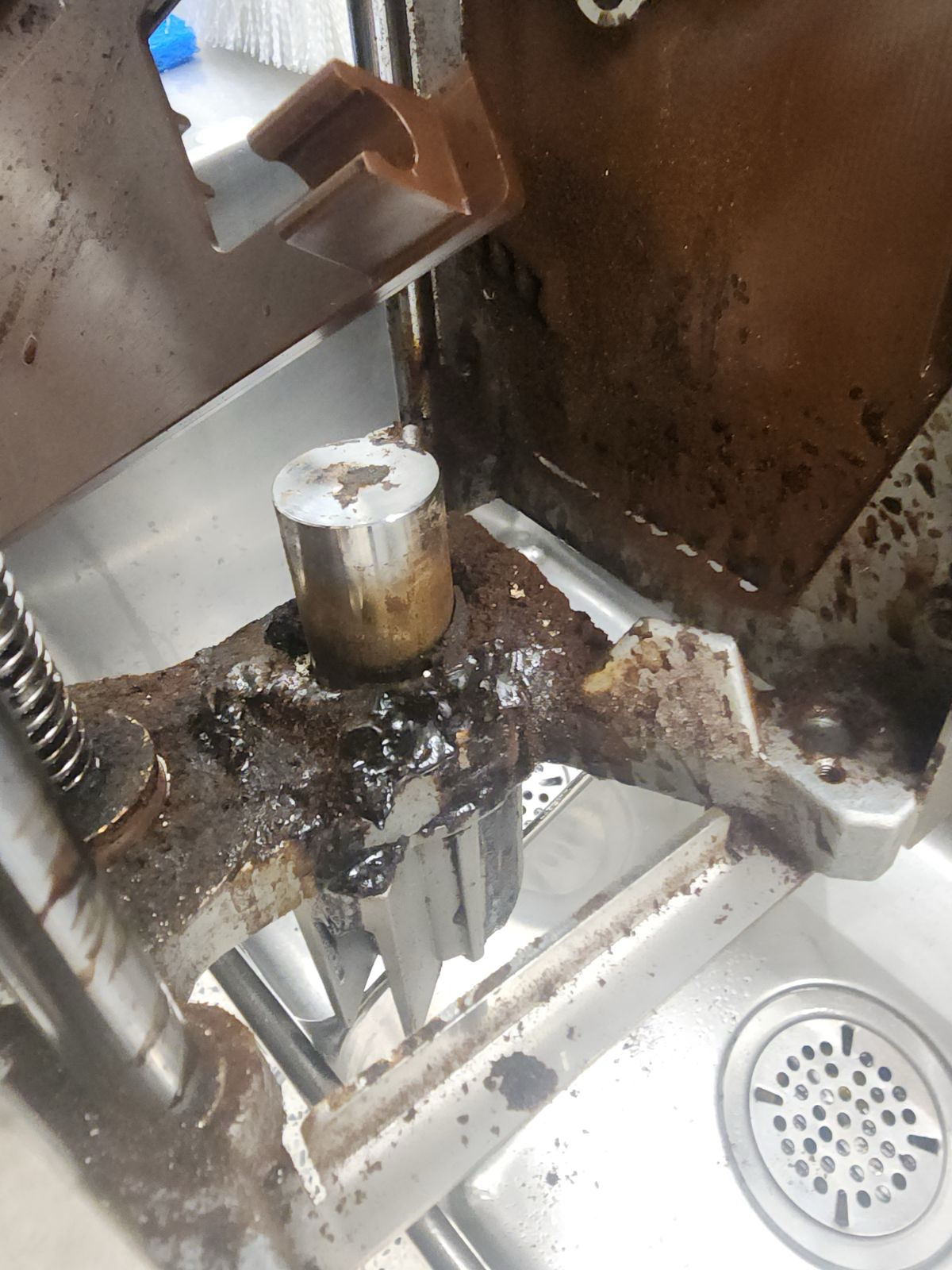 Dirty metal machine tool cutting or pressing a cylindrical part, with debris on the work surface