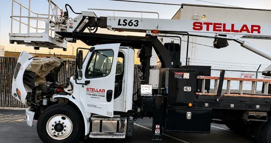 White Stellar utility truck with an elevated boom lift and damaged front end on a street
