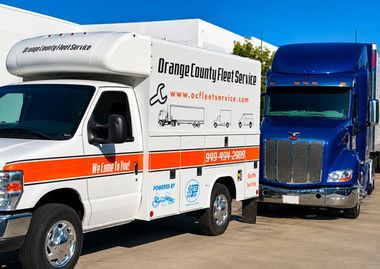 Orange-tinted photo of a white delivery van and box truck parked outdoors.