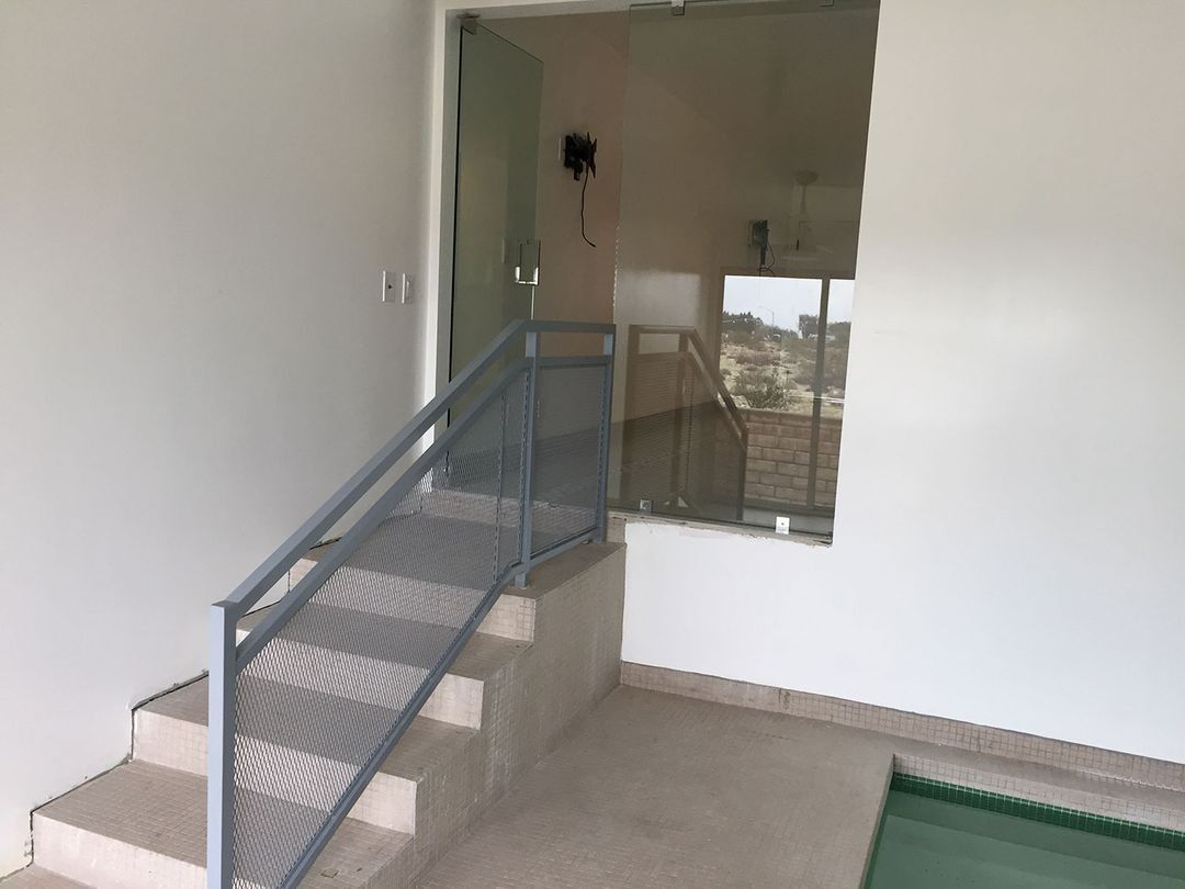 Indoor stairway with metal railing leading to a glass doorway in a bare room