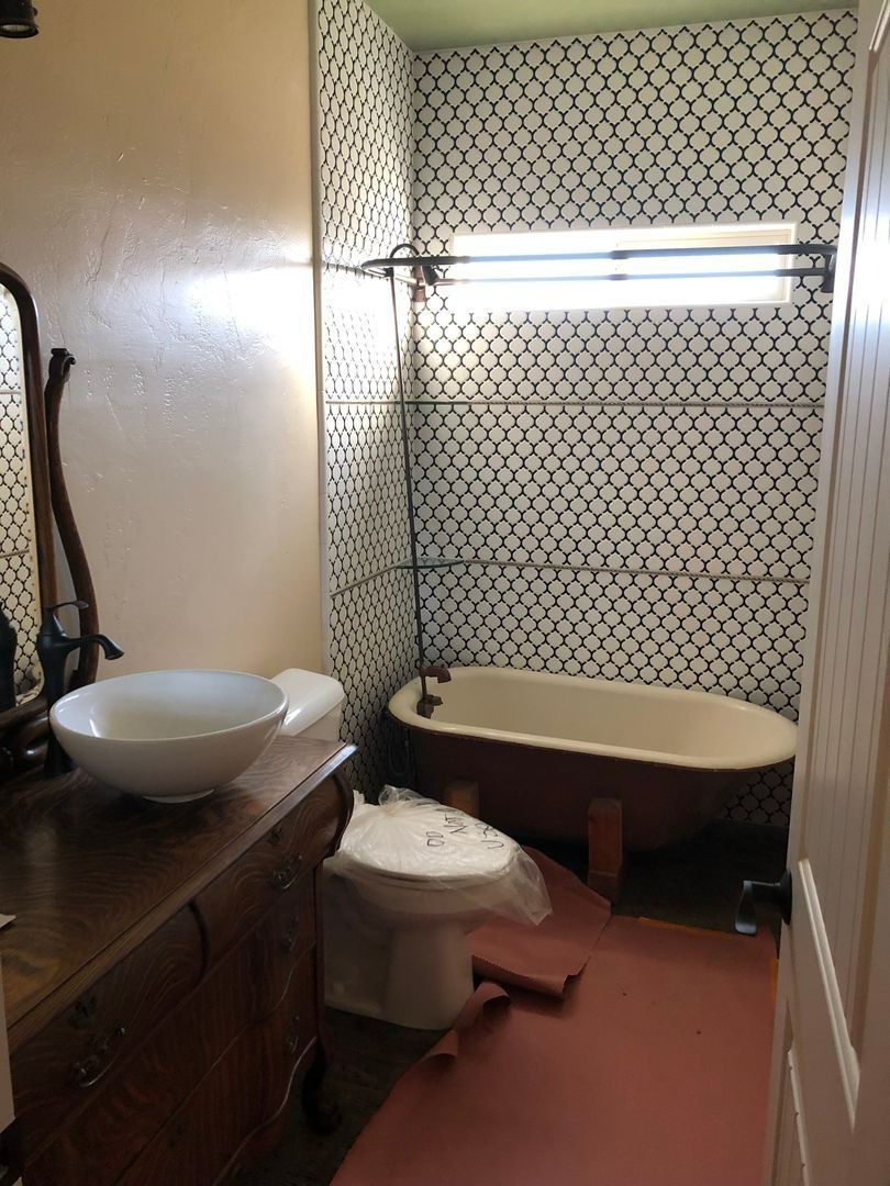 Small bathroom with sink, toilet, and bathtub in beige and brown tones.