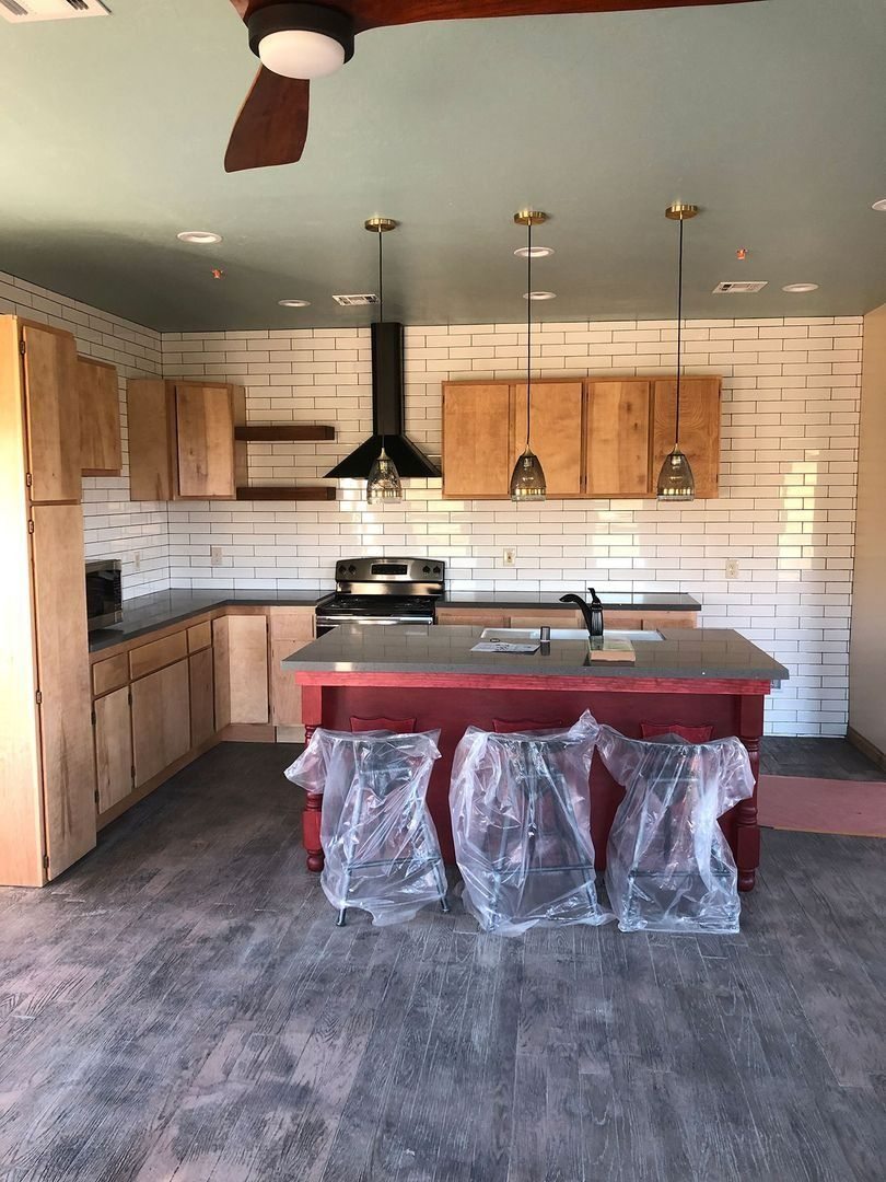 Small kitchen with wood cabinets, white shiplap walls, red island, and dark gray floor.