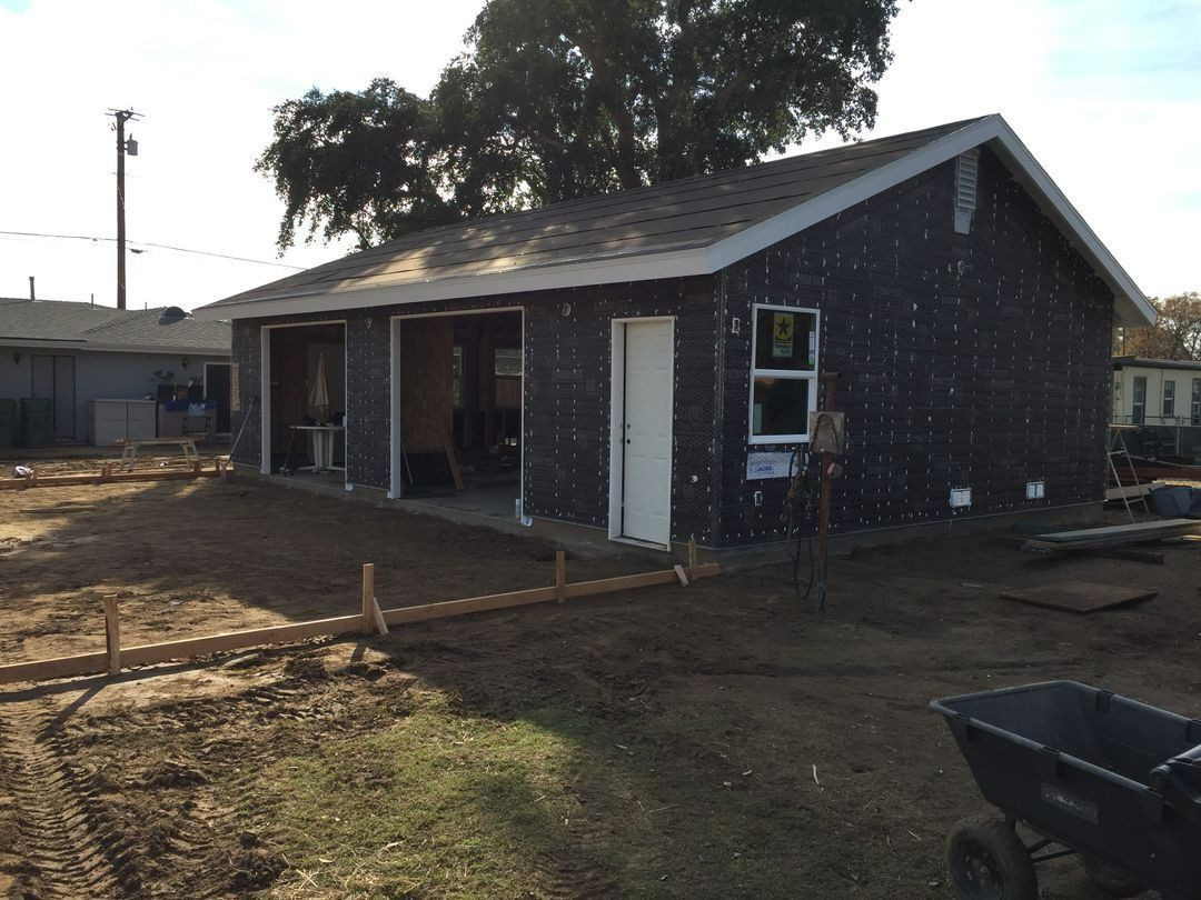 Small brick house with a front porch and white trim in a dirt yard at dusk