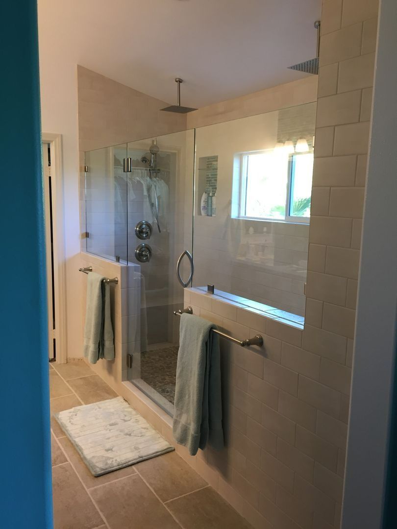 Modern bathroom with glass shower, double vanity, towels, and soft natural light