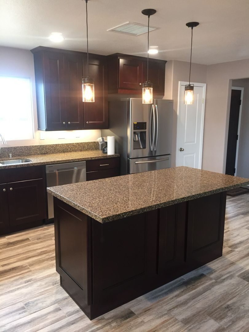 Modern kitchen with dark cabinets, granite island, stainless steel appliances, and pendant lights