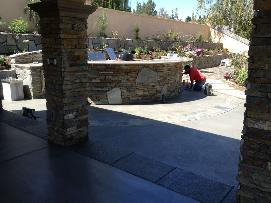 Stone patio with a circular outdoor fountain and a person in a red shirt crouching nearby.