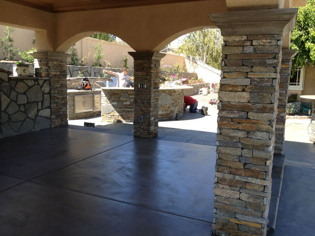 Stone-pillared patio with shaded concrete floor and desert landscape beyond