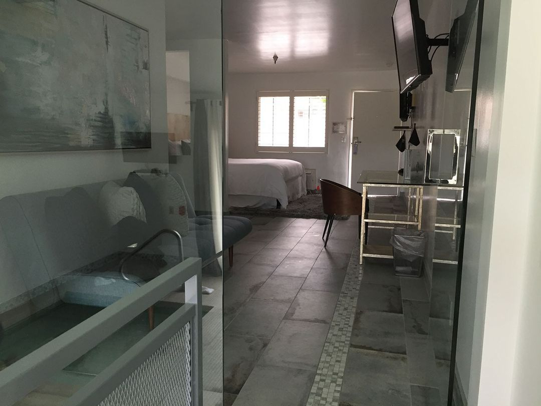 Narrow hallway leading to a bright bedroom, with glass cabinets on the left and a small table on the right.