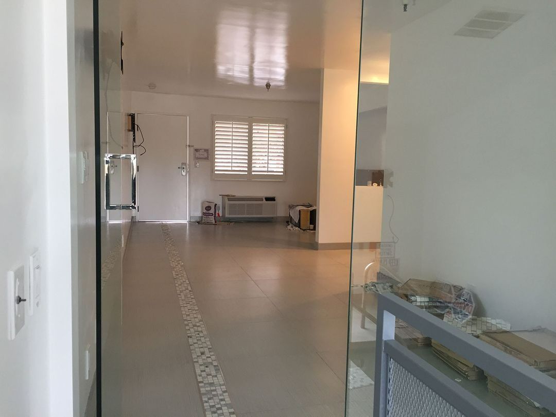 Bright hallway with white walls, tiled floor, window light, and a glass display case on the right