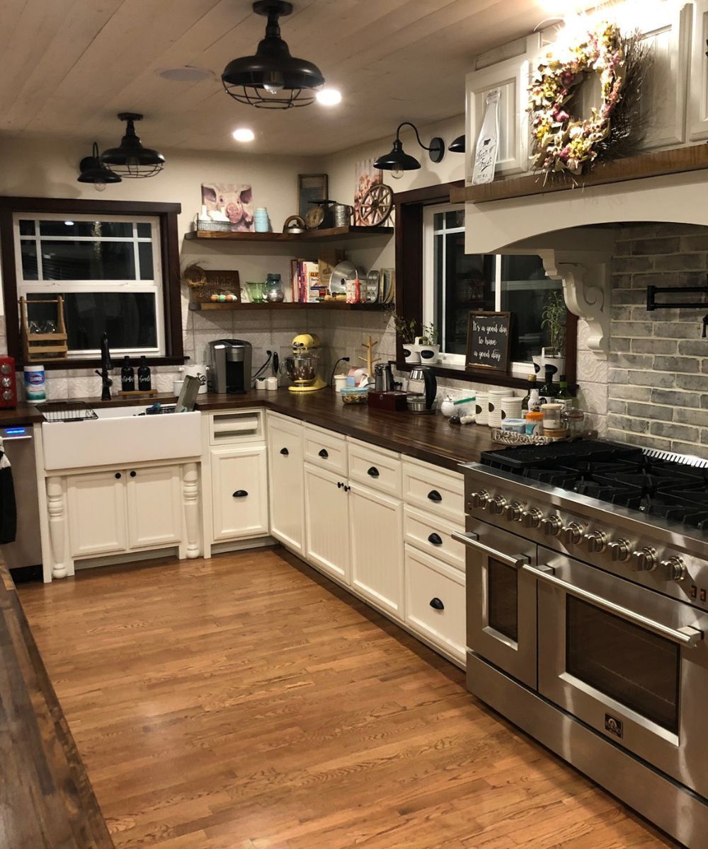 Cozy farmhouse kitchen with white cabinets, stainless stove, wood floor, and brick backsplash