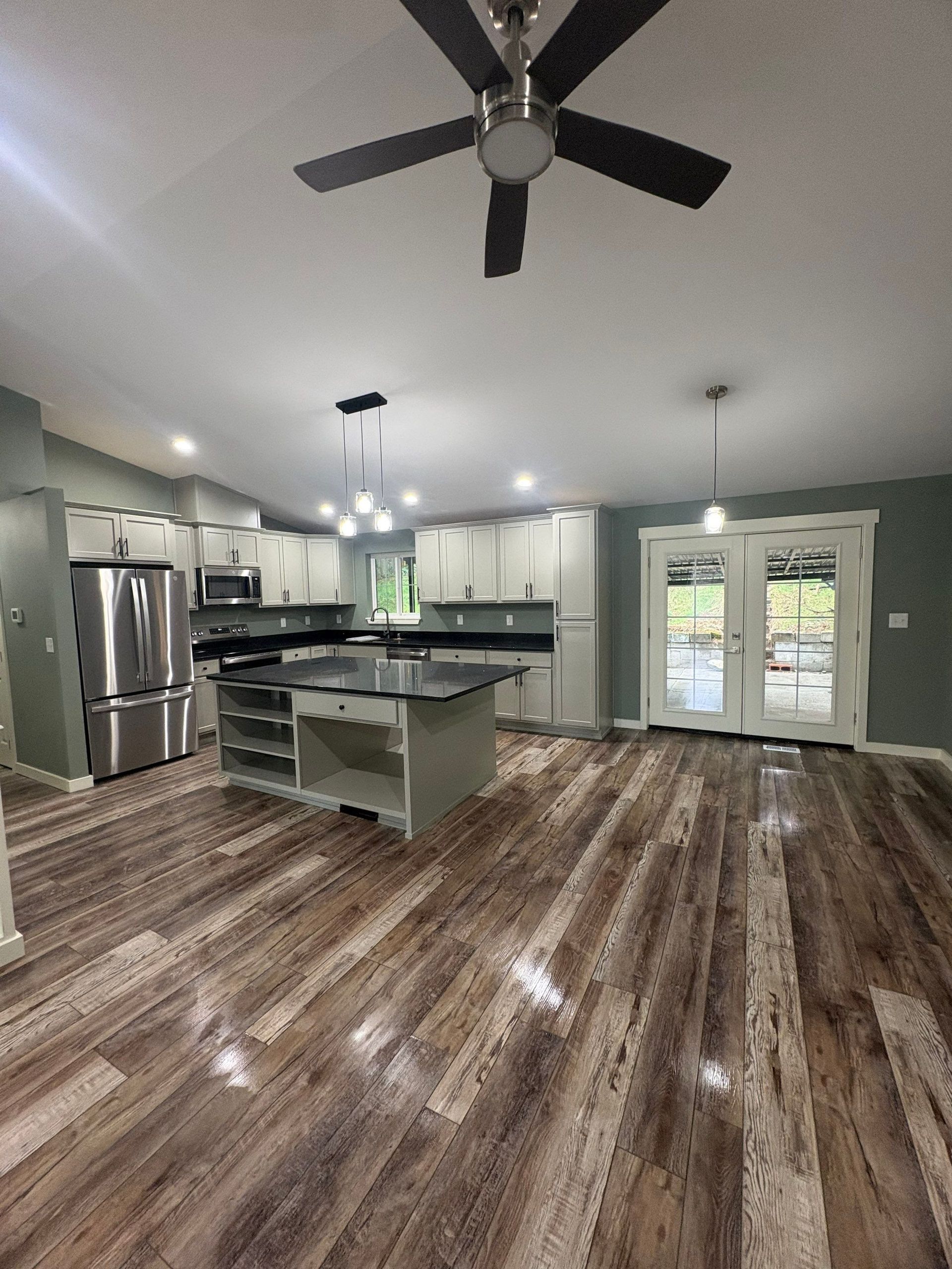 Modern kitchen with island, stainless steel appliances, white cabinets, wood floors, and French doors