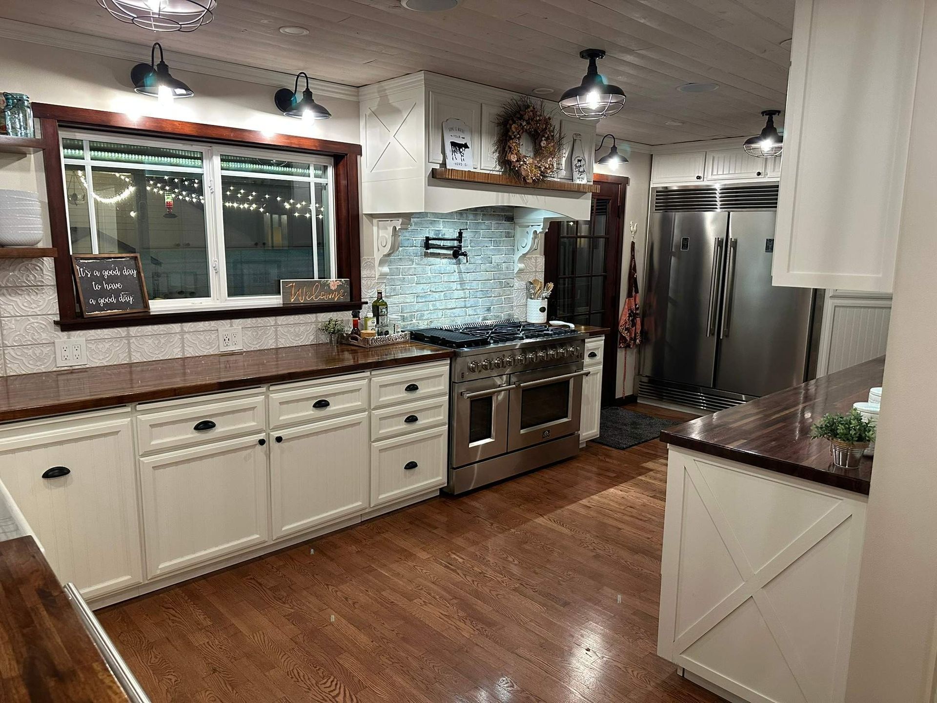 Modern kitchen with white cabinets, stainless steel appliances, wood floors, and a window over the sink