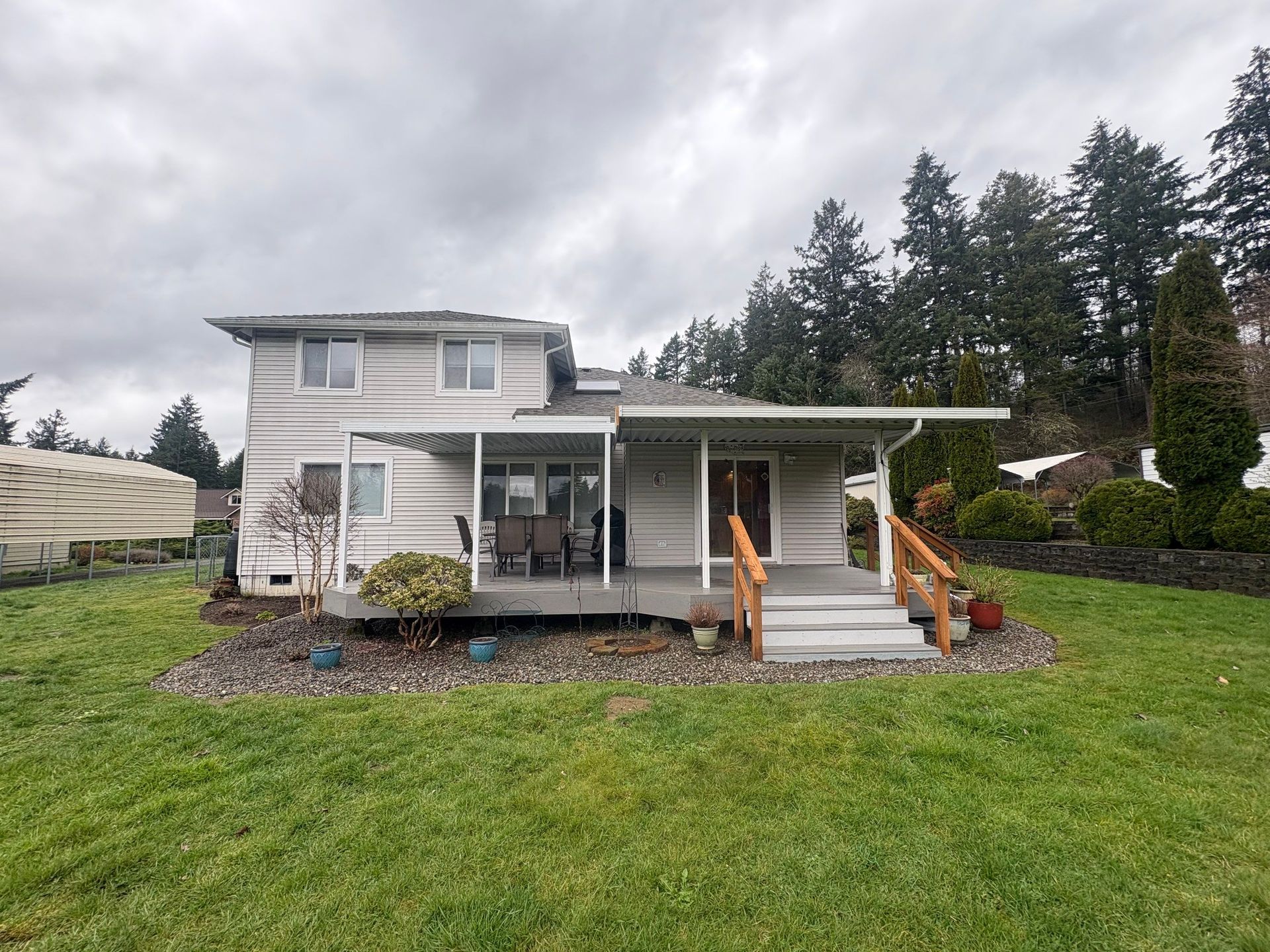 Two-story white house with a covered porch and front steps in a grassy yard under cloudy skies