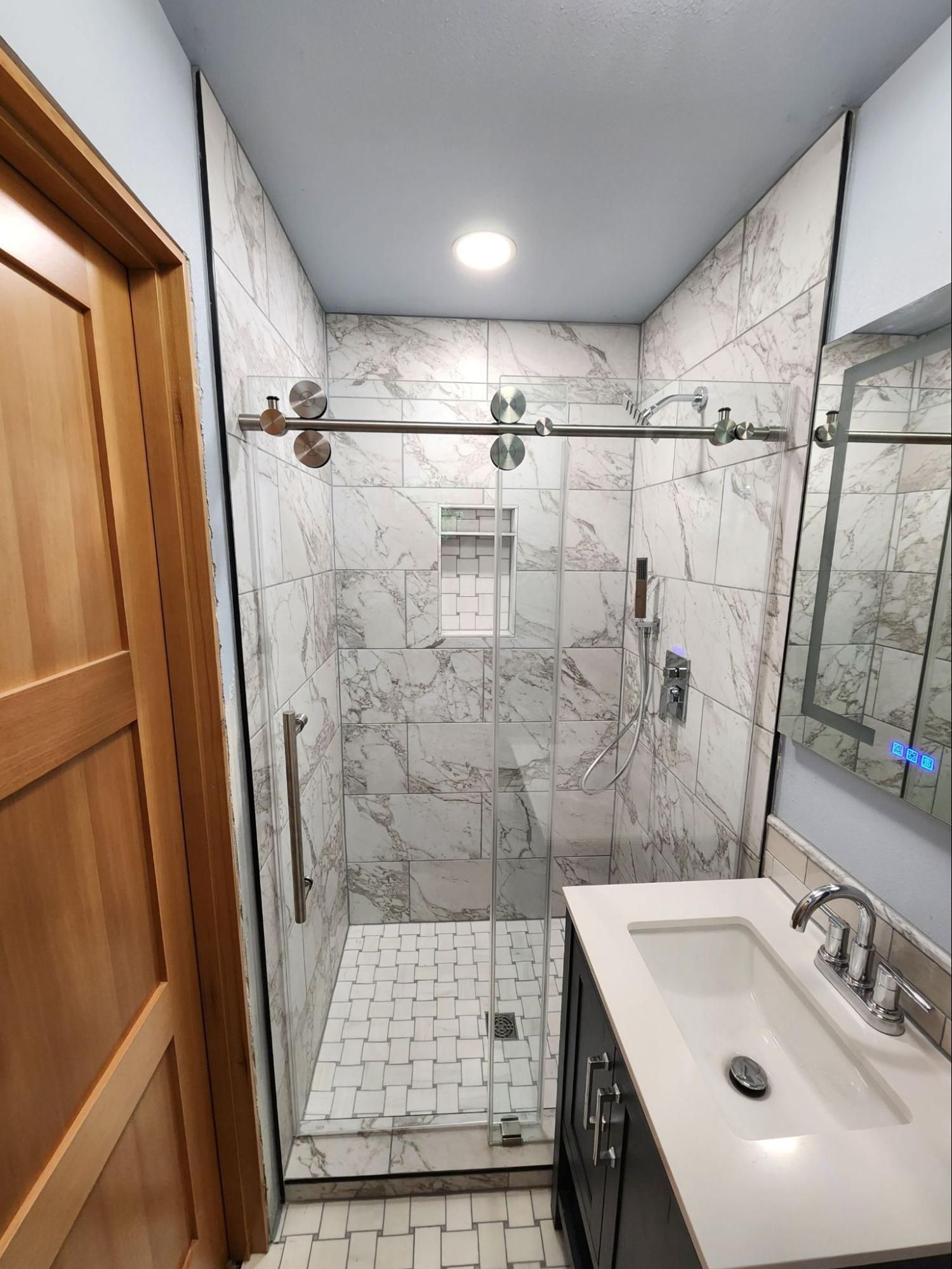 Modern bathroom with glass shower, marble tiles, and a white sink