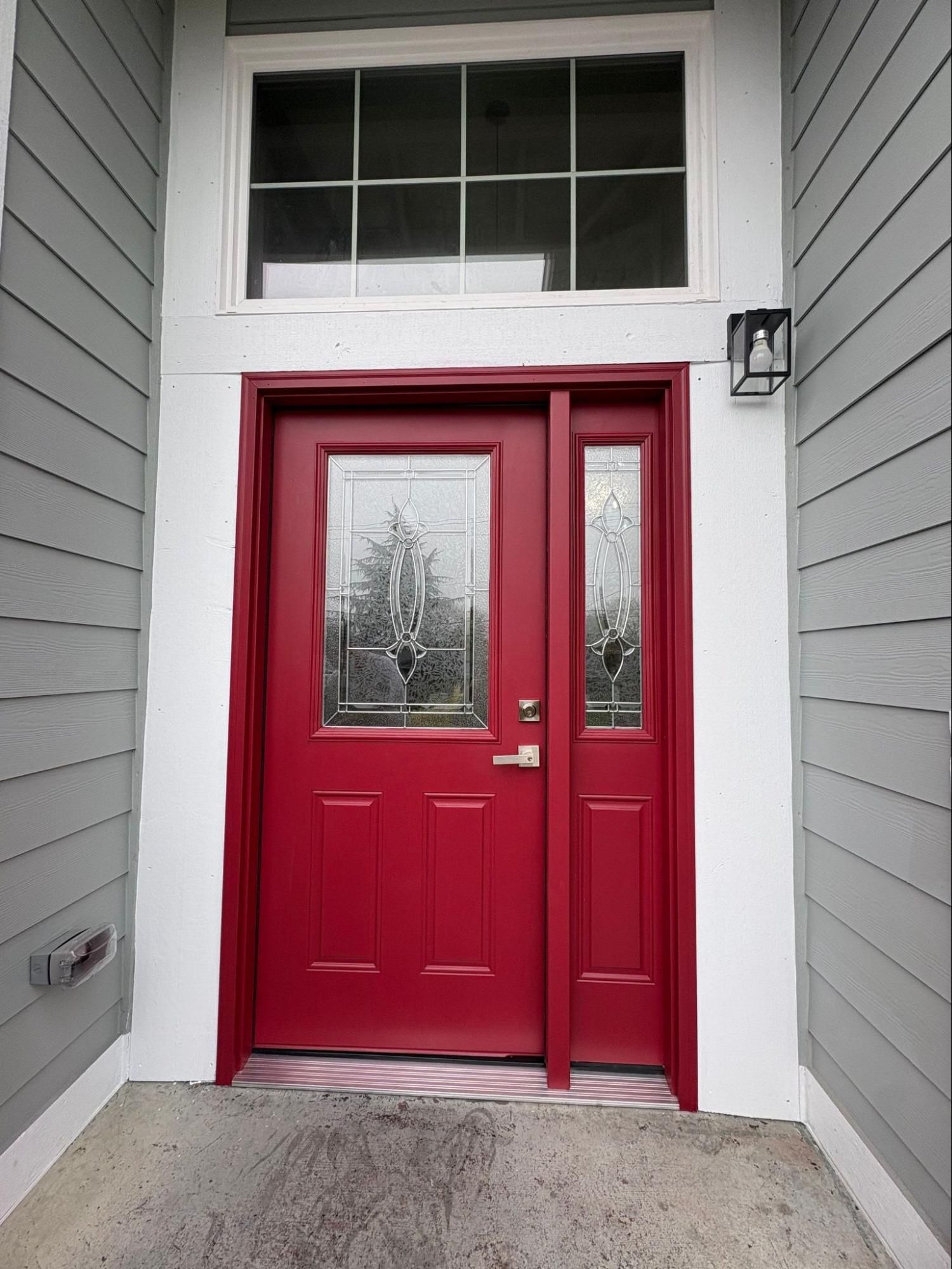 Red front door with glass panels in a gray house entryway