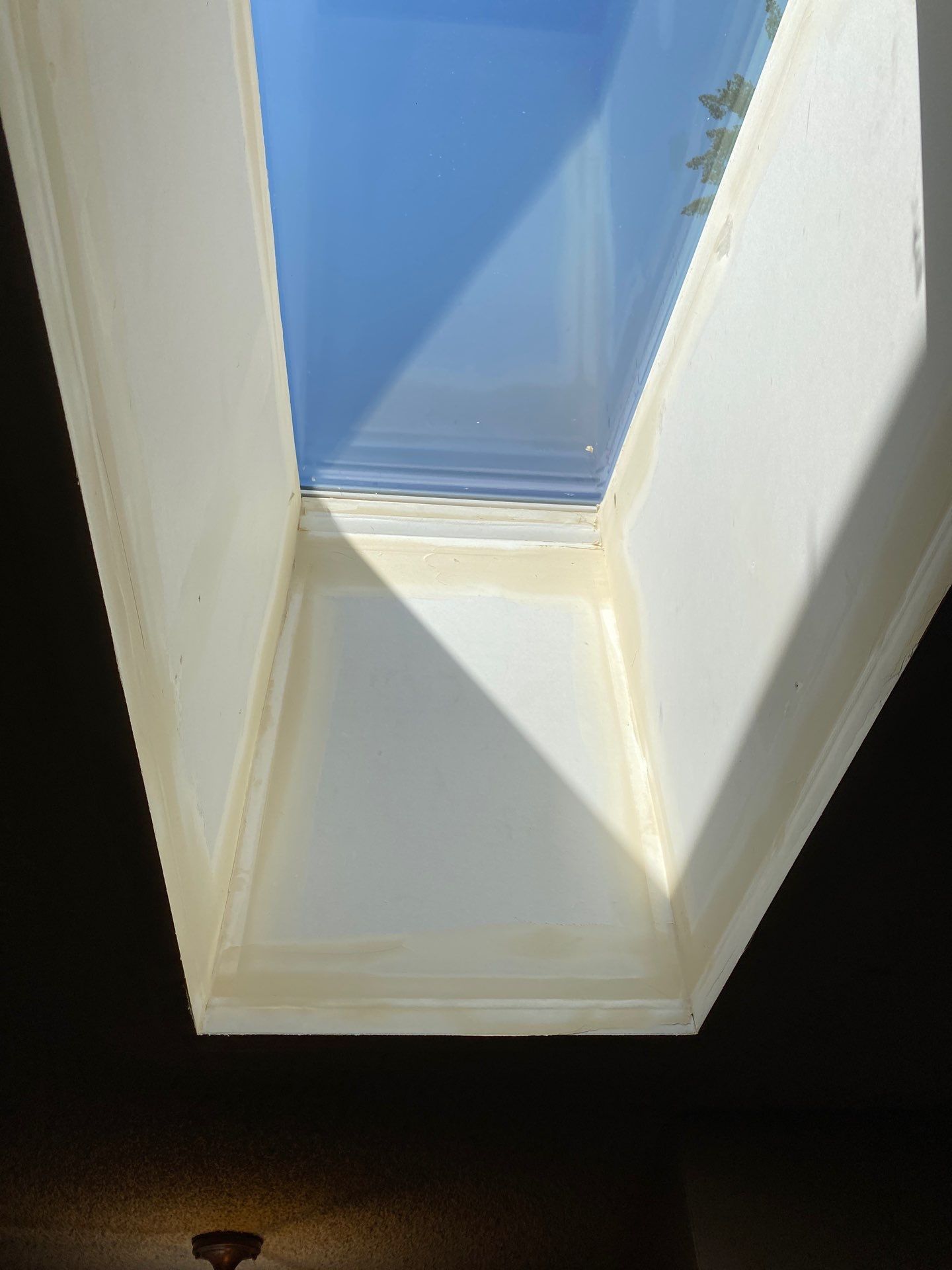 Skylight with blue sky, framed by white slanted interior walls