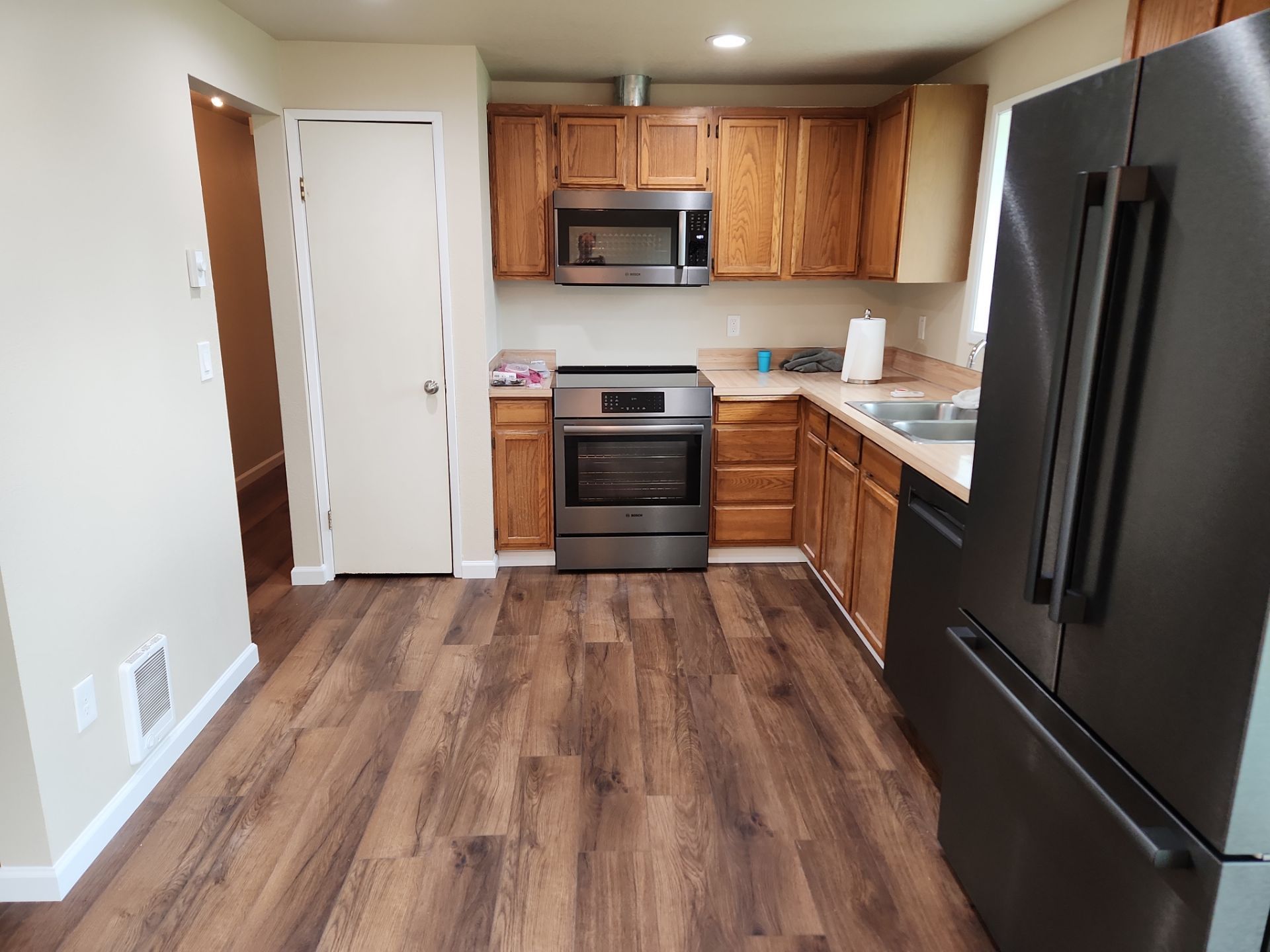 Empty kitchen with wood cabinets, black appliances, and wood-look flooring