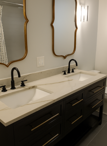 Double vanity bathroom sink with black faucets, dark cabinets, and gold-framed mirrors