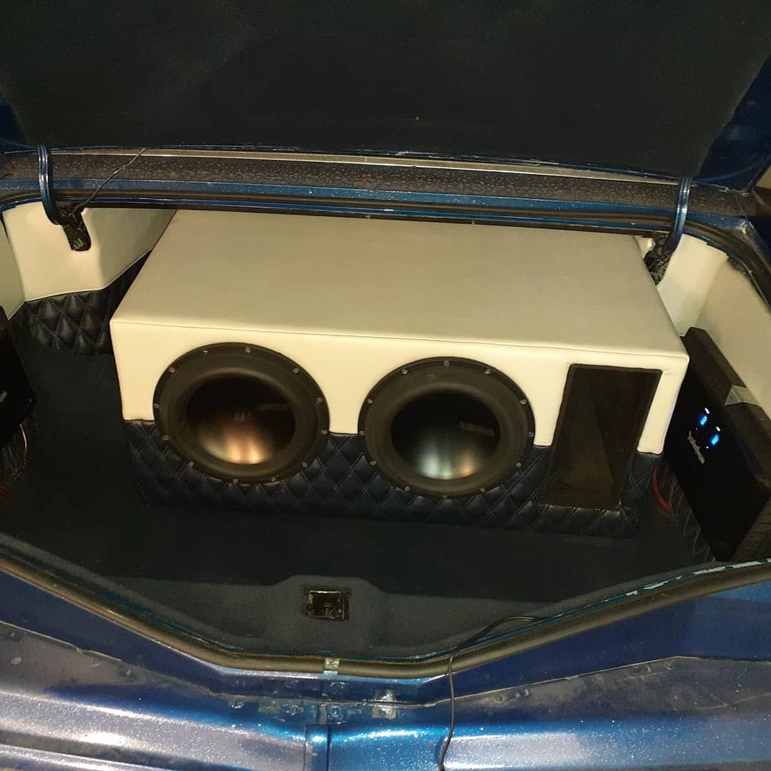 Car trunk with custom subwoofer box; two subwoofers and an amplifier are mounted. The interior is blue and gray.