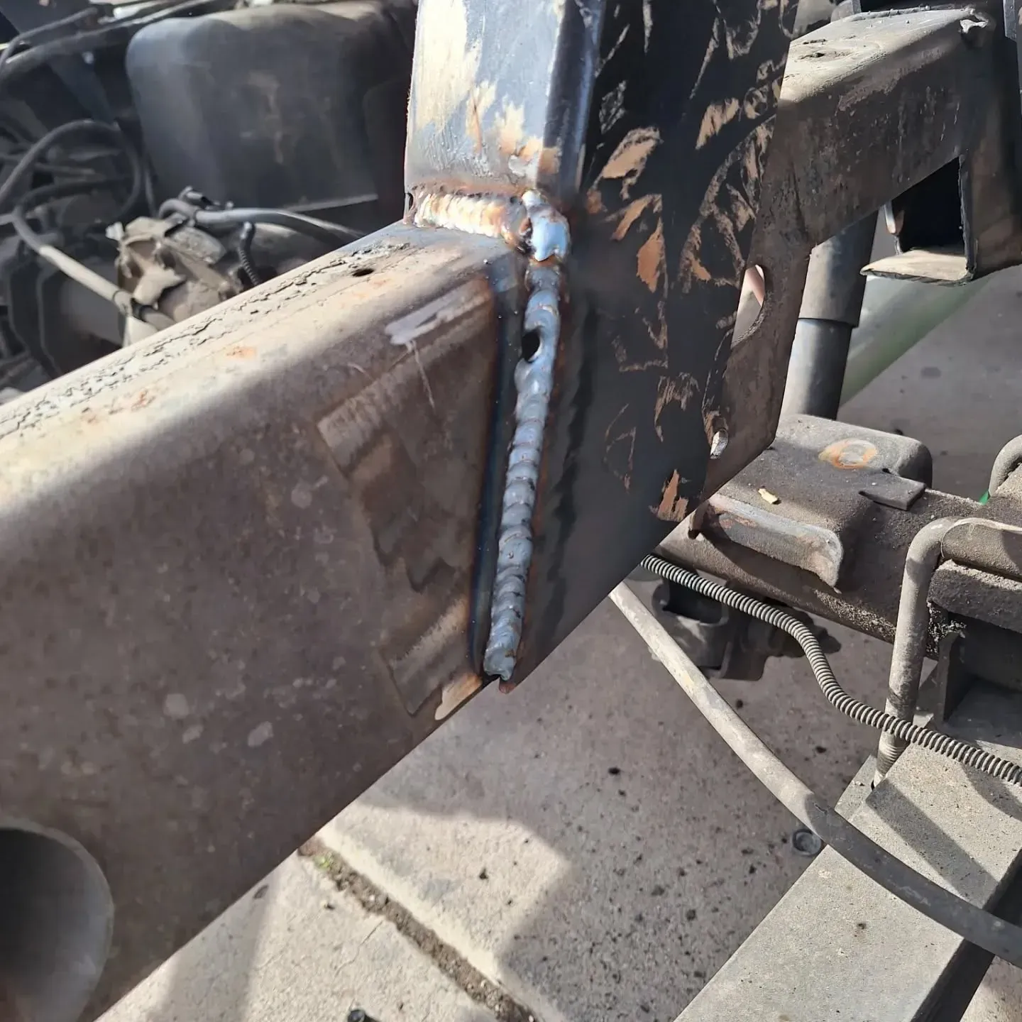 Close-up of a welded metal beam. Dark metal frame has a vertical plate 