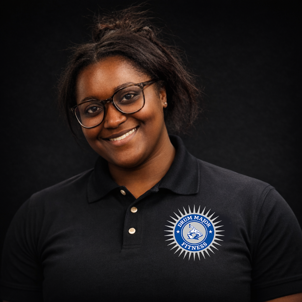 A smiling person wearing glasses and a black polo shirt with a blue circular emblem on the chest against a black background.