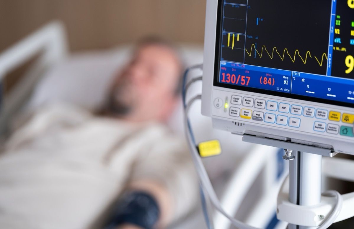 Hospital patient in bed with monitor displaying vital signs in the foreground
