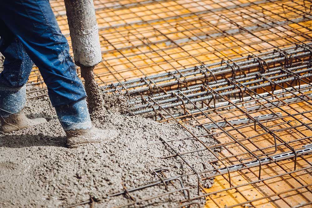 A Man is Pouring Concrete on a Construction Site — Dampier Street Landscape Supplies in Taminda, NSW