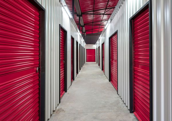 Red storage unit doors line a gray hallway. Red storage unit doors line a gray hallway.