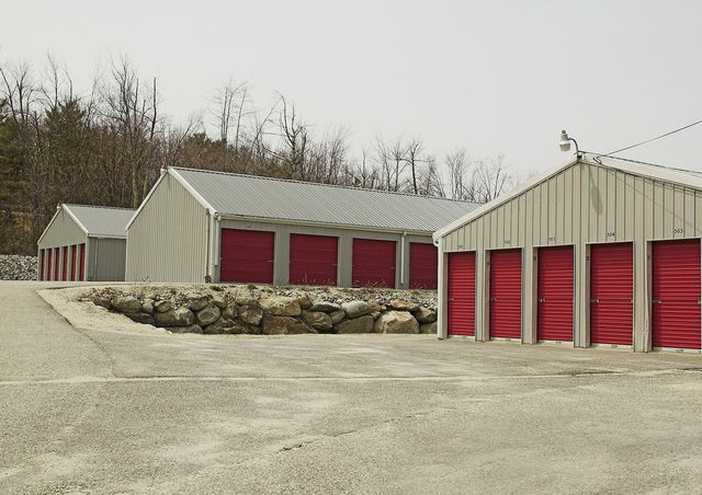 Storage units with red doors and corrugated metal roofs.