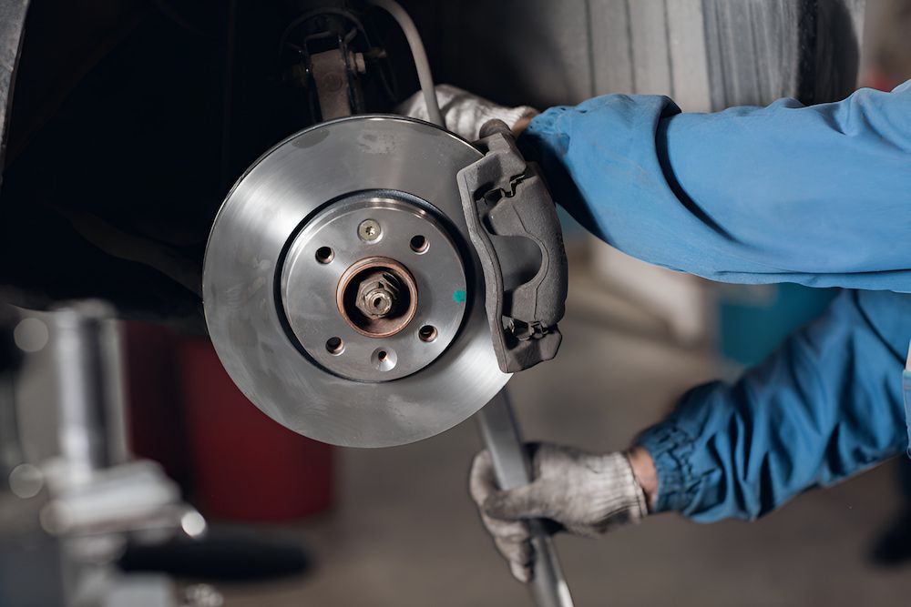 A Mechanic Is Fixing A Brake Disc On A Car — 100% Automotive In South Nowra, NSW