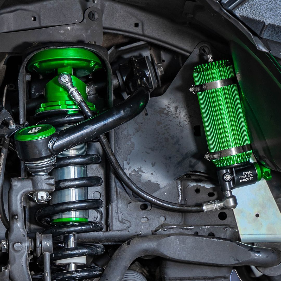 Green aftermarket suspension components on a vehicle's undercarriage. — 100% Automotive In South Nowra, NSW
