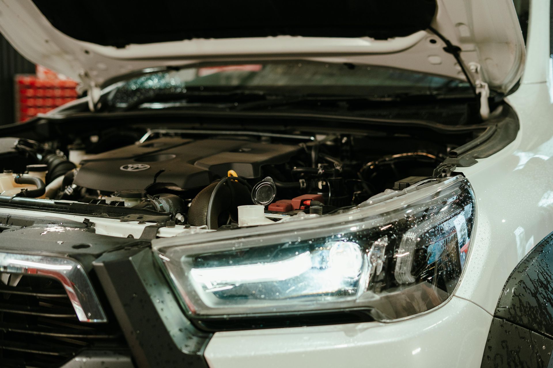 White pickup truck with hood open, engine visible, and bright headlights. β 100% Automotive In South Nowra, NSW