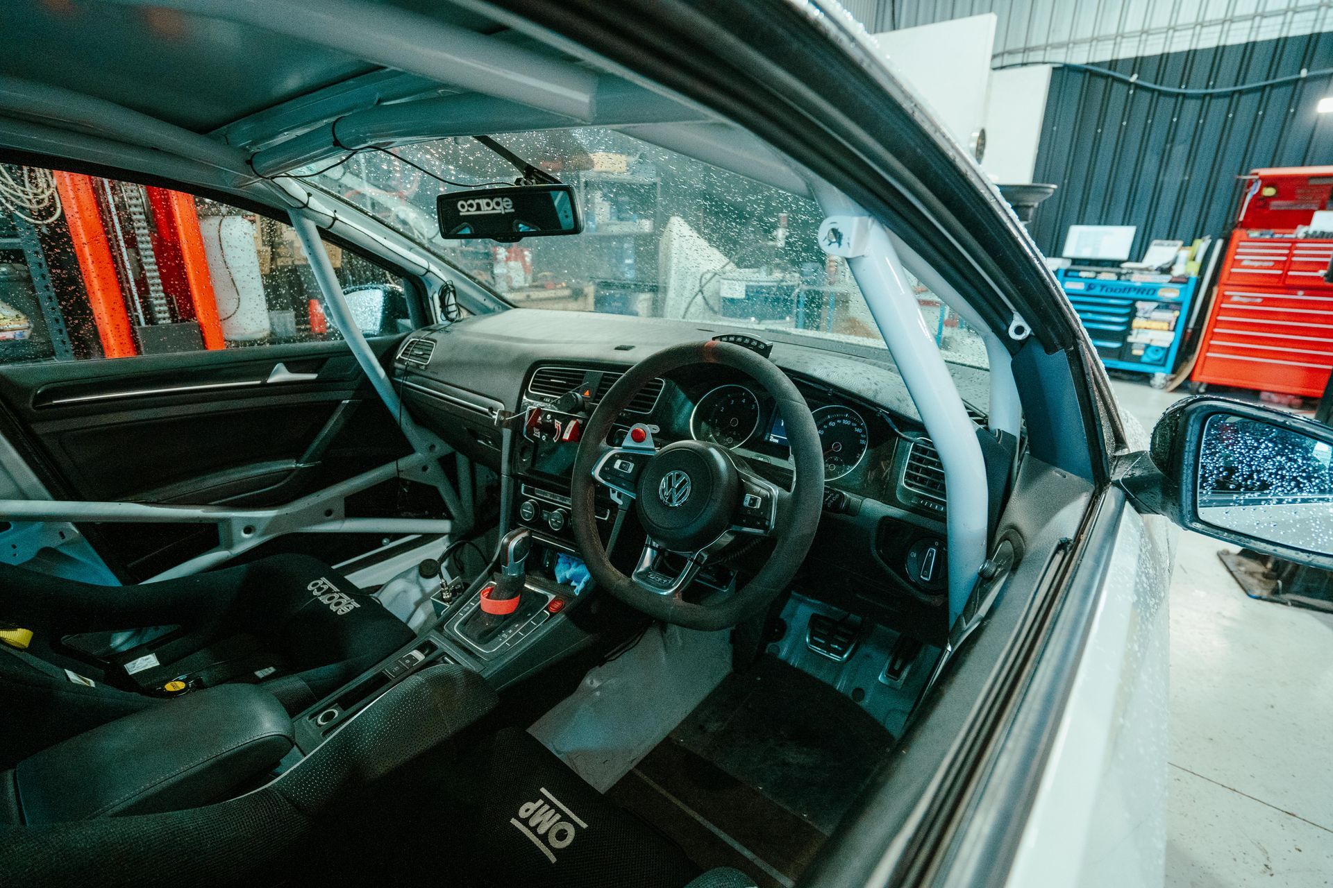 Interior view of a race car with roll cage, racing seats, steering wheel, and dashboard. — 100% Automotive In South Nowra, NSW