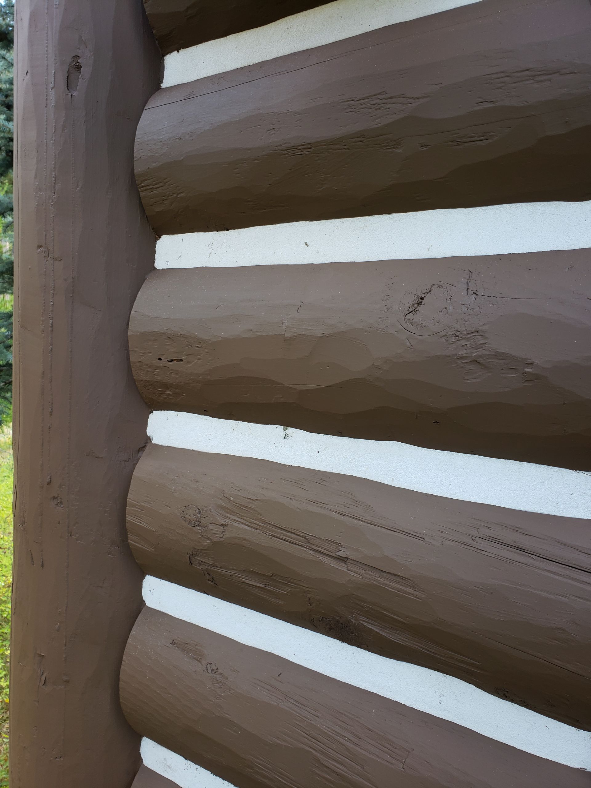 Close-up of a brown log railing with horizontal wooden beams and white gaps between them