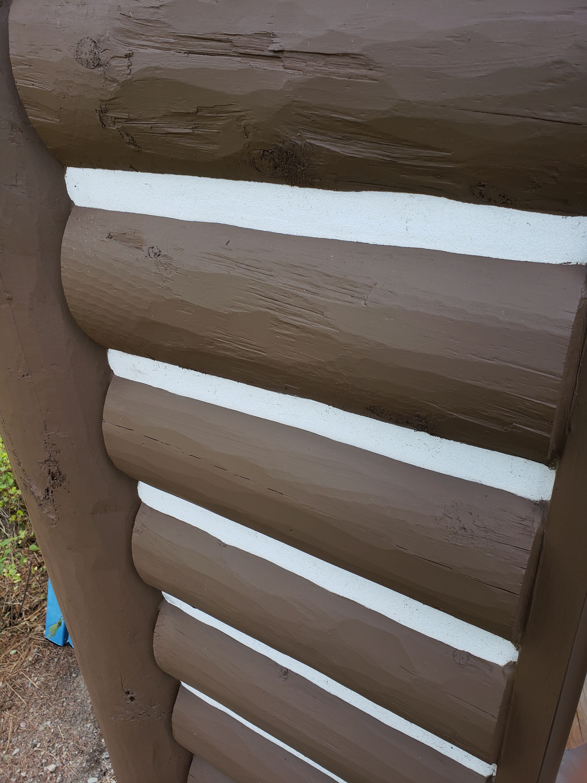 Close-up of brown log cabin wall with stacked rounded logs and white mortar gaps
