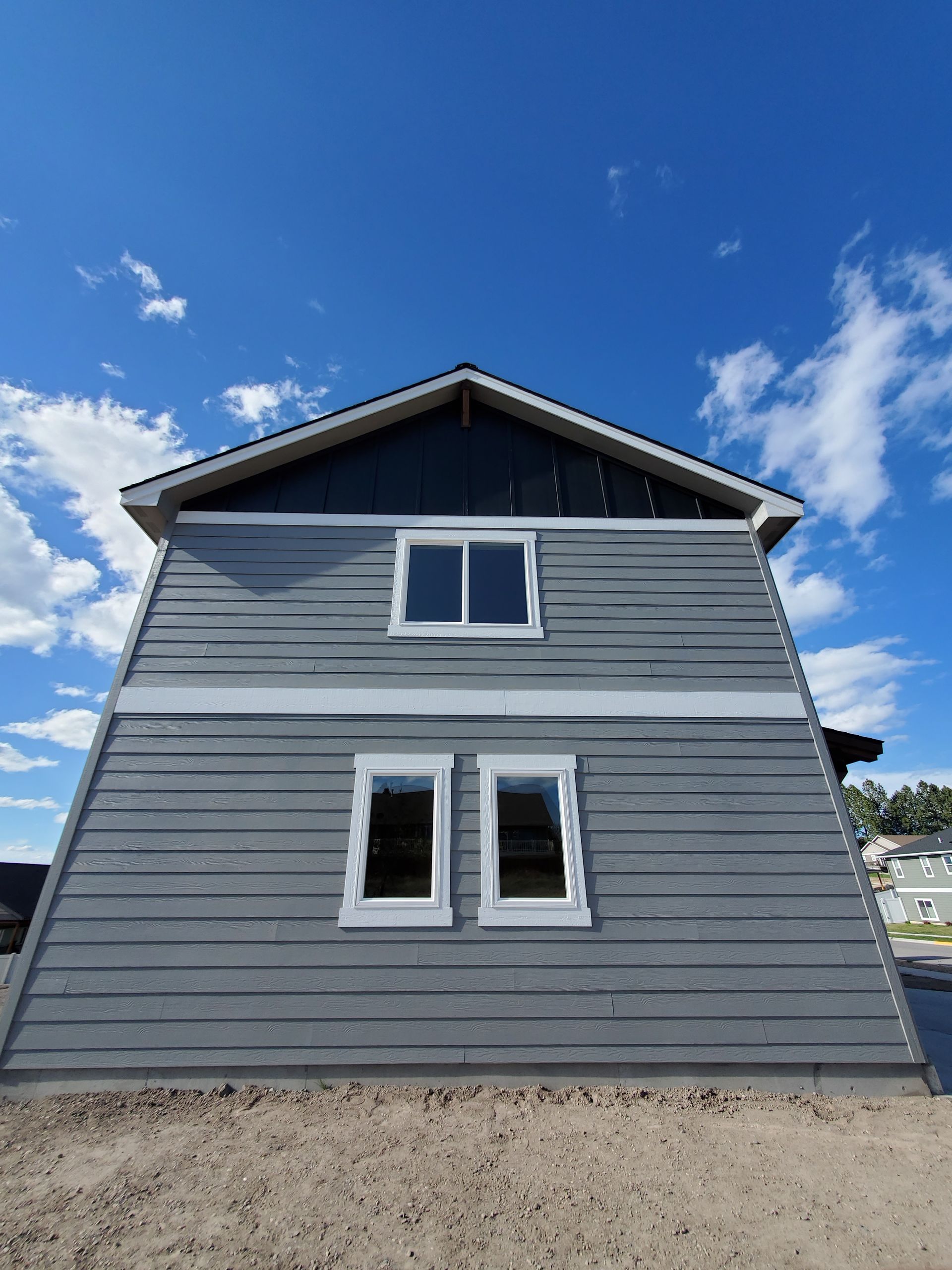 Gray house exterior with two windows under a blue sky
