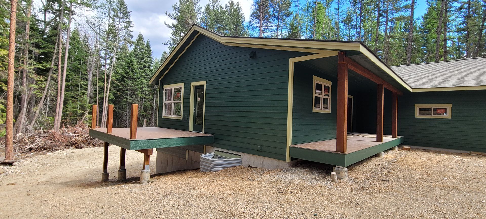 Green cabin with porch and ramp in a wooded campground
