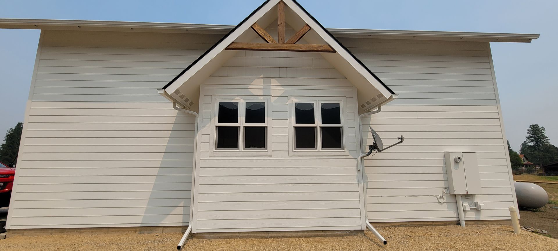 Small white house exterior with a central entrance and gabled roof under construction or repair